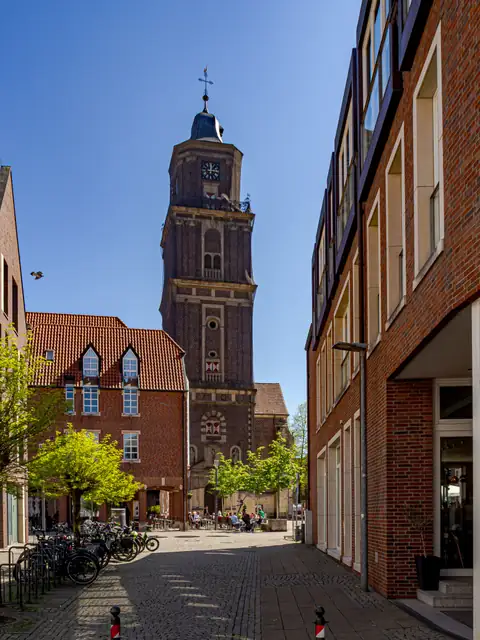 Blick durch die Fußgängerzone von Coesfeld auf den Turm von St. Lamberti unter blauem Himmel